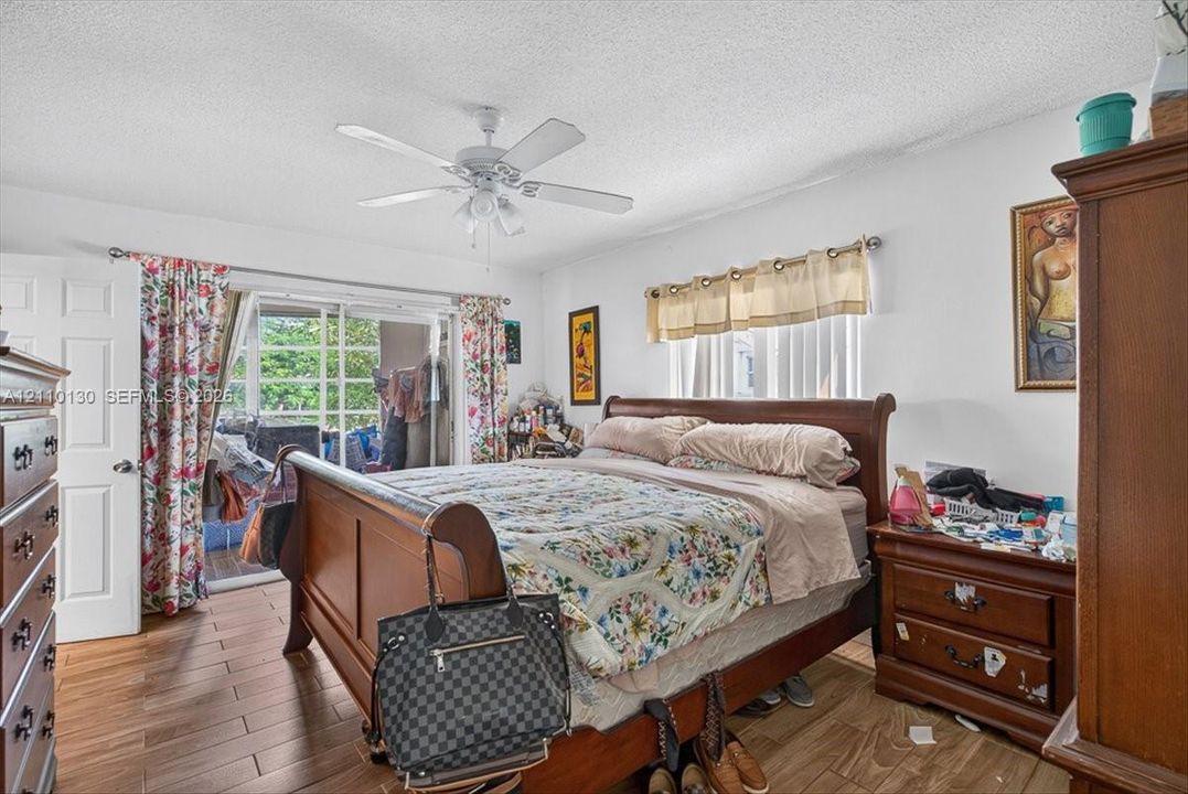 Wood-finish tile flooring, ceiling fan with integrated lighting, and sliding glass patio door