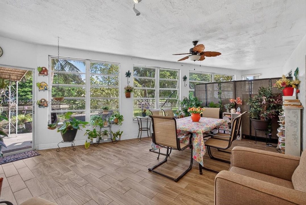 Sunroom featuring wood-finish tile flooring, a ceiling fan, and extensive windows with integrated crank-style hardware