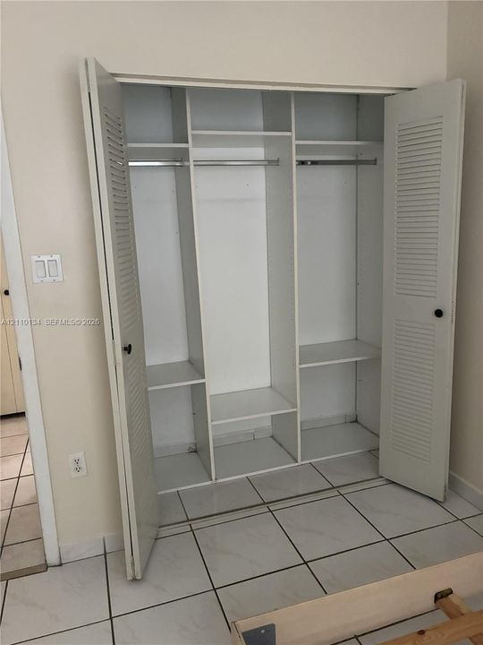 Spacious reach-in closet featuring triple-section organization with multiple shelving levels, hanging rods, and louvered bi-fold doors for convenient access and storage capacity