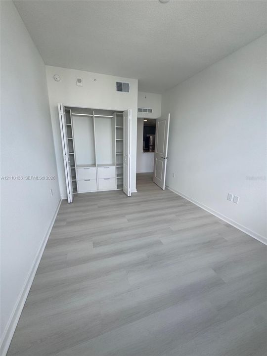 Interior space featuring wood-finish flooring and a built-in closet system with integrated shelving and drawer storage