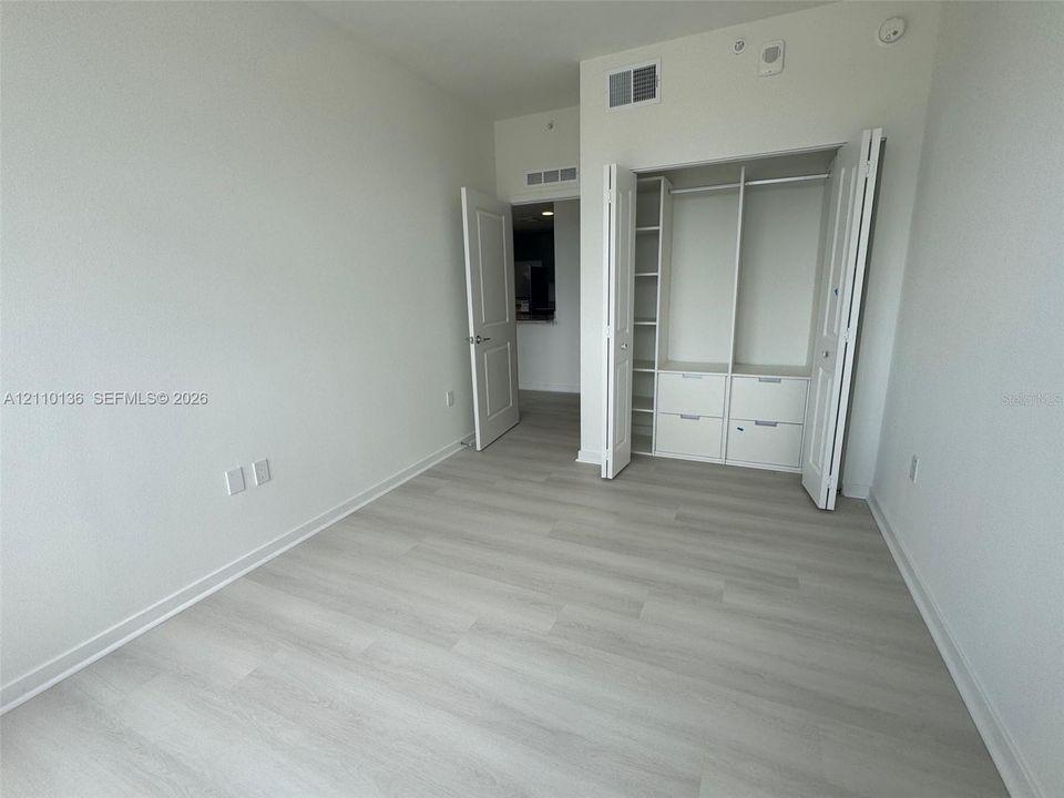 Wood-finish flooring, interior closet with custom built-in shelving and drawers, and paneled swinging door