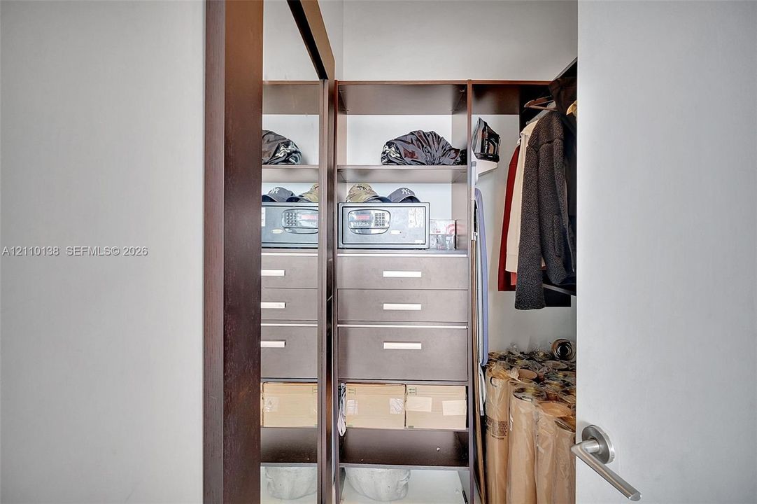 Walk-in closet featuring custom built-in cabinetry, tiered shelving, integrated storage drawers, and a full-length mirror