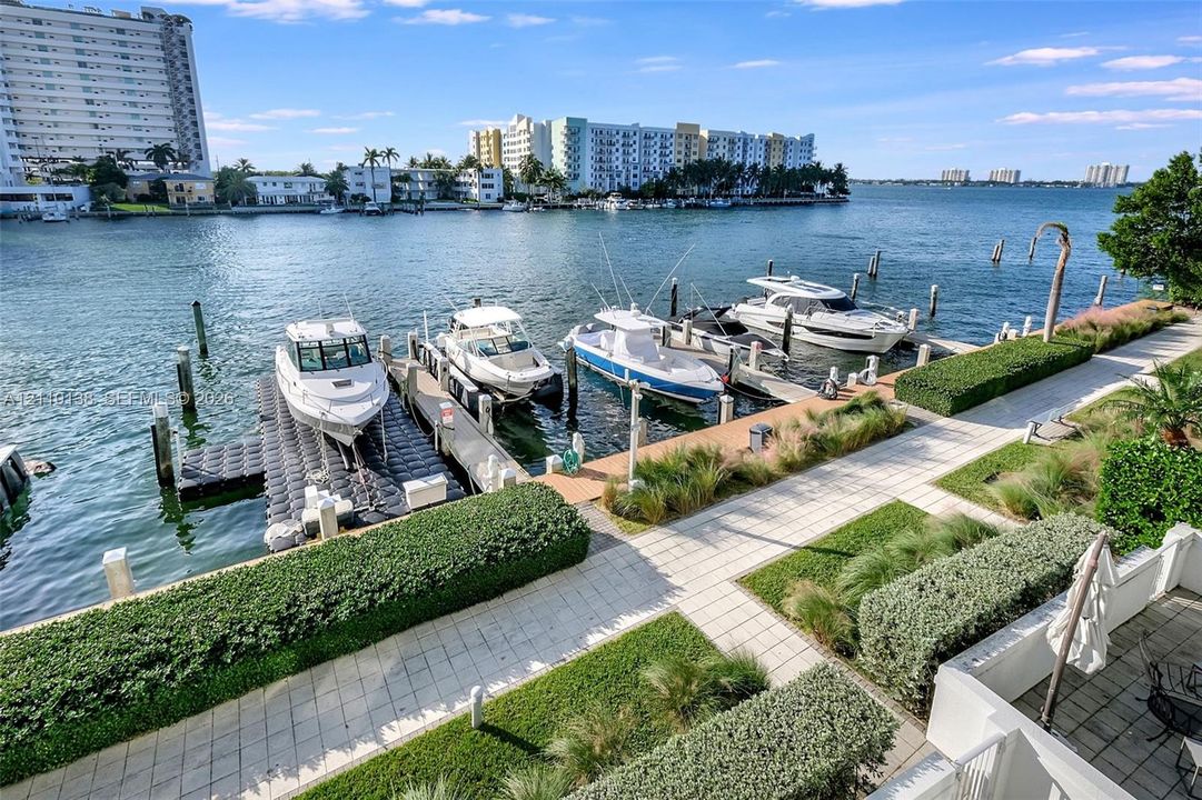 Waterfront property featuring a private boat slip, dock infrastructure, manicured landscaping, and paved pedestrian walkways