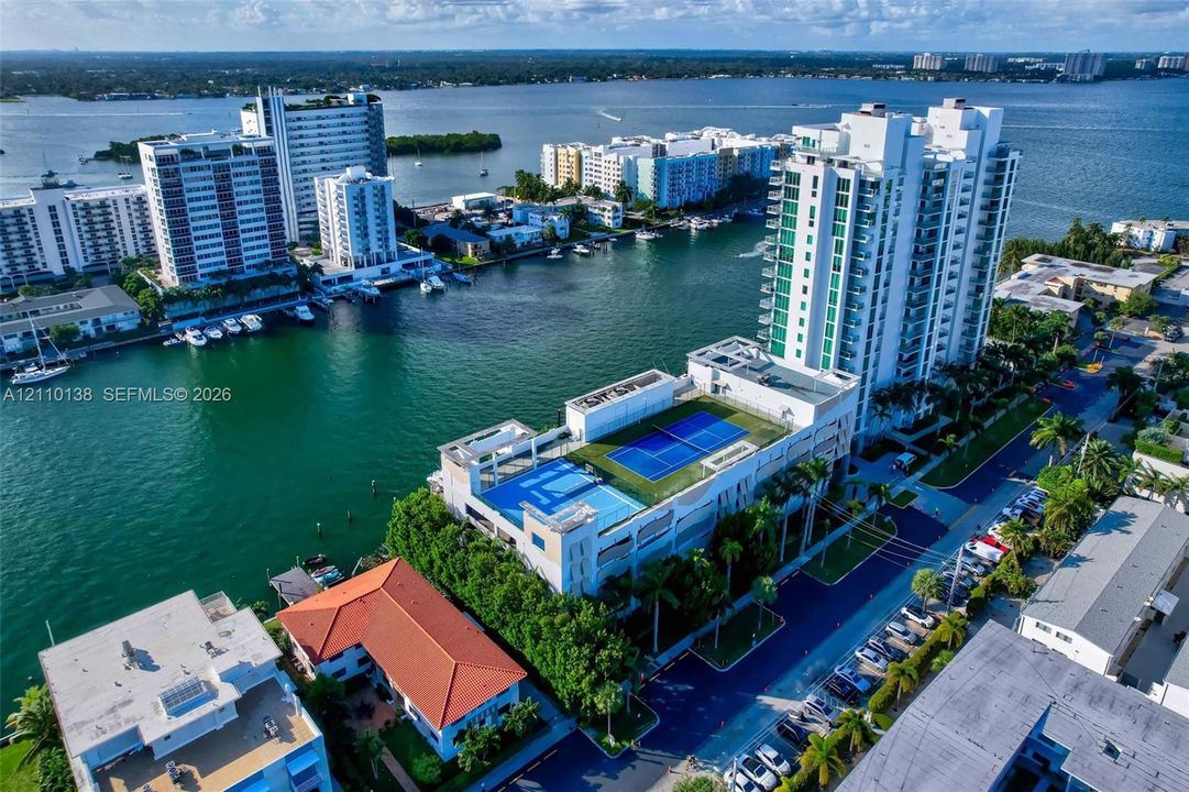 High-rise waterfront property featuring a rooftop tennis court and swimming pool, situated along a deep-water canal