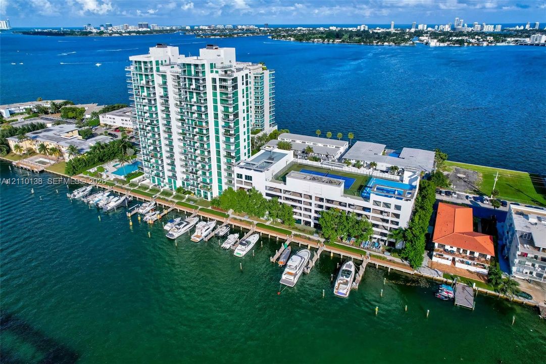 Waterfront high-rise property featuring deep-water boat slips, expansive open-air balconies, a rooftop swimming pool, and dedicated parking structures