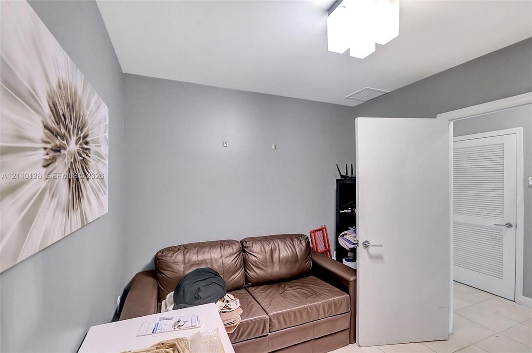 Interior space featuring neutral wall paint, tile flooring, a multi-panel ceiling light fixture, and a white louvered door