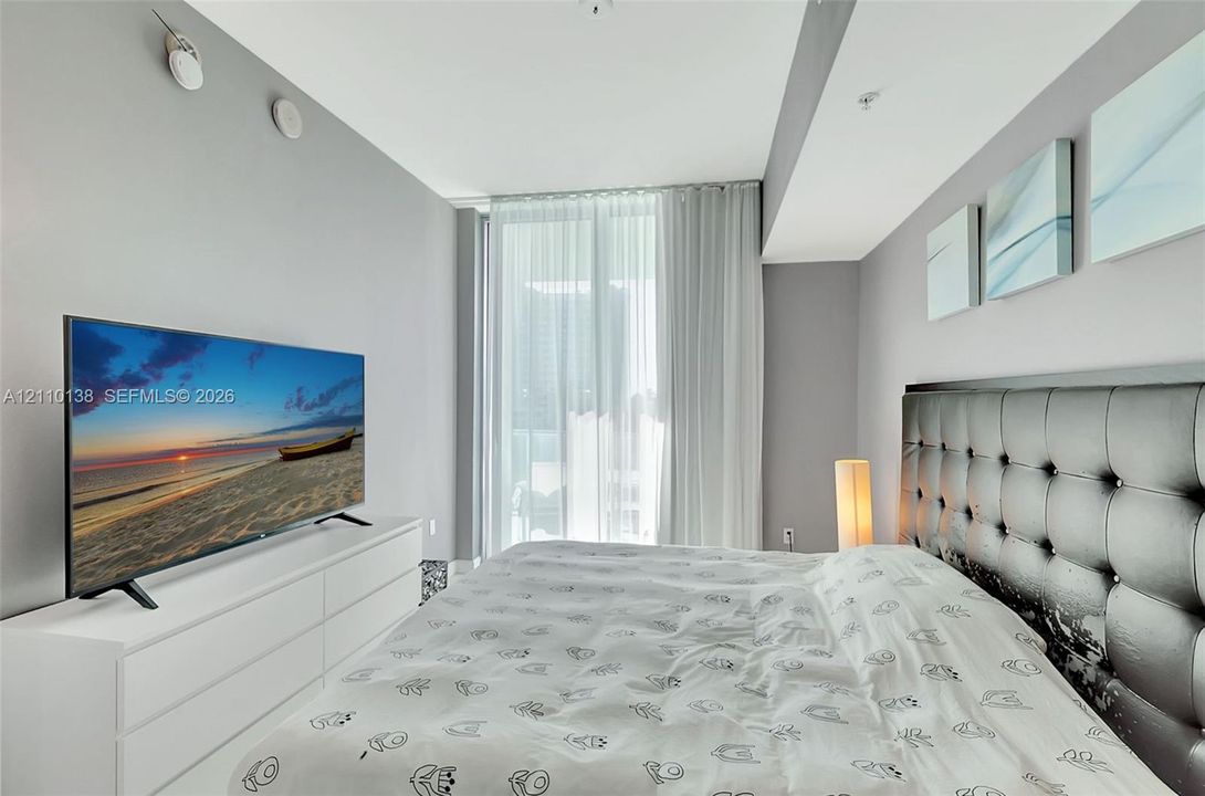 Floor-to-ceiling glass door with full-length window treatments and high-contrast neutral wall finishes