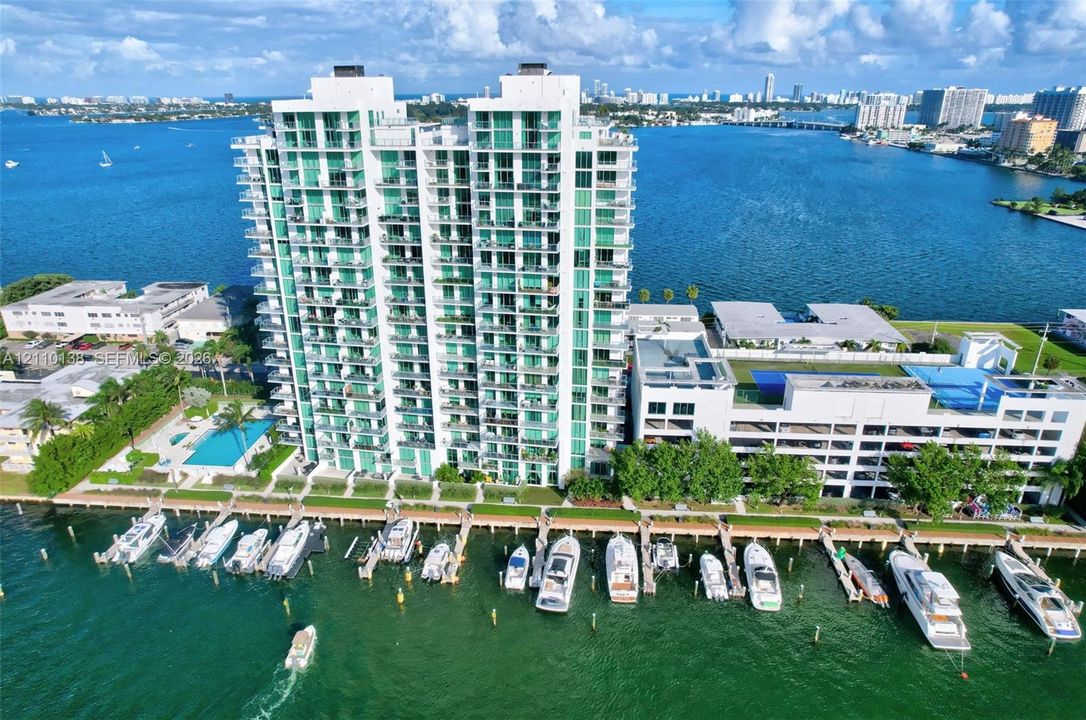 High-rise building featuring wrap-around balconies, private boat slips, swimming pool, and multi-level parking structure situated on the waterfront