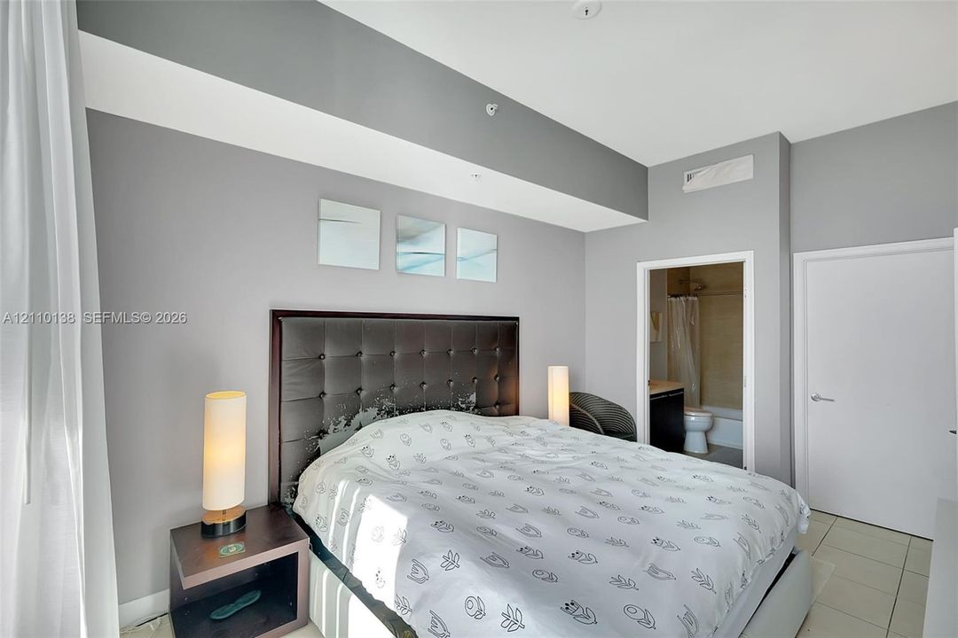 Neutral grey wall finish, high ceilings with recessed lighting, and large-format tile flooring