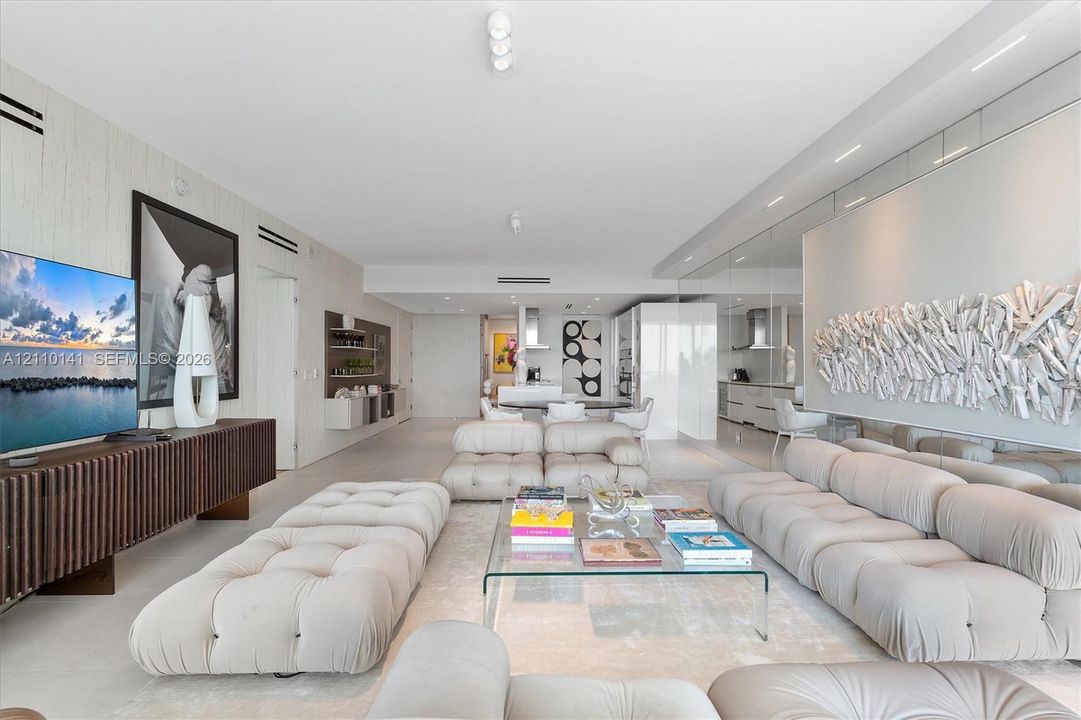 Open-concept interior featuring smooth solid-surface flooring, full-wall mirrored accents, recessed ceiling lighting, and custom linear built-in cabinetry