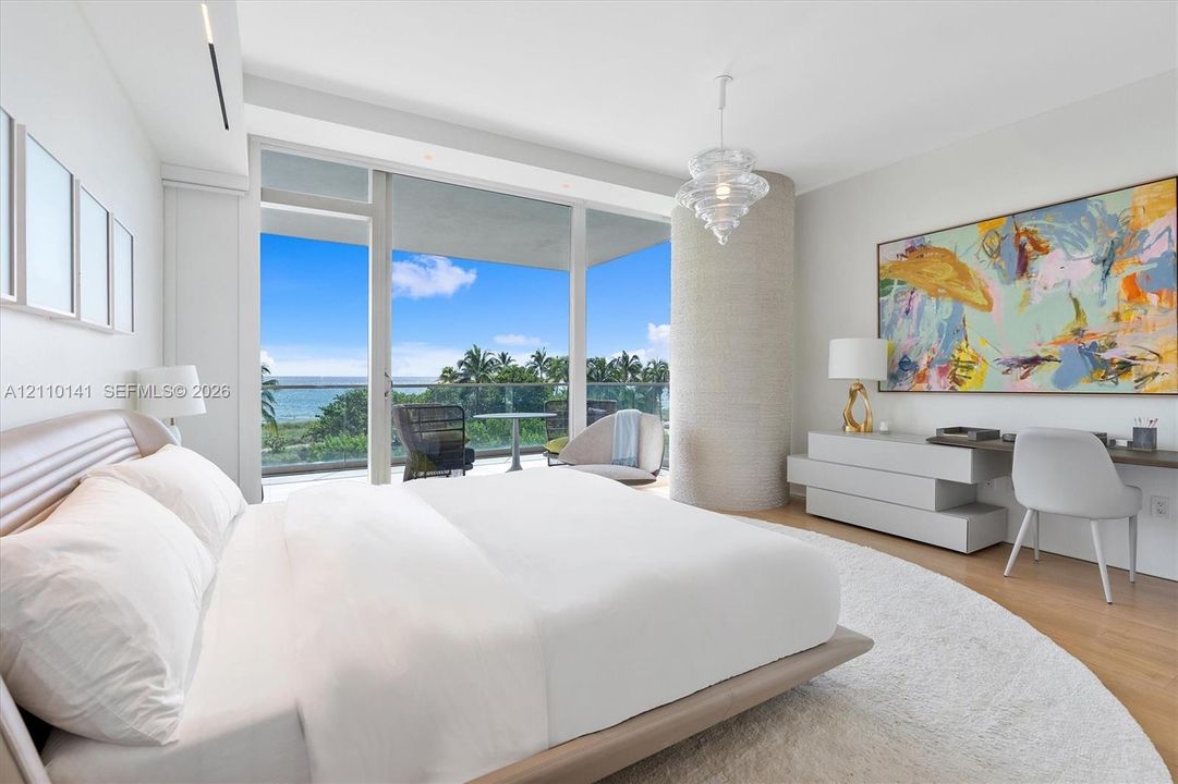 Floor-to-ceiling glass doors, wood-finish flooring, cylindrical architectural column with textured finish, pendant light fixture, and glass-railed private balcony