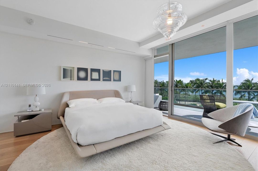 Floor-to-ceiling sliding glass doors, private balcony, wood-finish flooring, recessed lighting, and sculptural glass pendant fixture