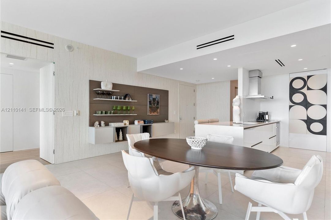 Open-concept interior, recessed ceiling lighting, a kitchen island with stone countertops, and built-in wall cabinetry