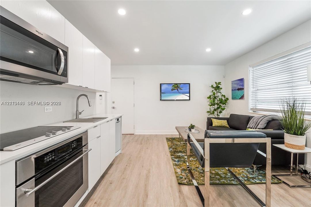 Kitchen featuring white flat-panel cabinetry, stainless steel appliances, recessed lighting, and wood-finish flooring