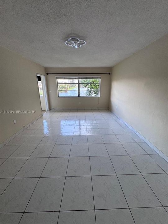 Neutral-toned interior space featuring light-colored square tile flooring and a ceiling-mounted flush light fixture
