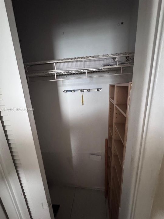 Storage area featuring wire shelving, a mounted hardware rack, and built-in vertical wooden shelving units