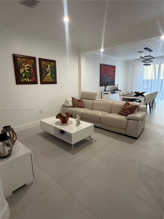 Large-format neutral tile flooring, recessed ceiling lighting, and modern geometric pendant lighting
