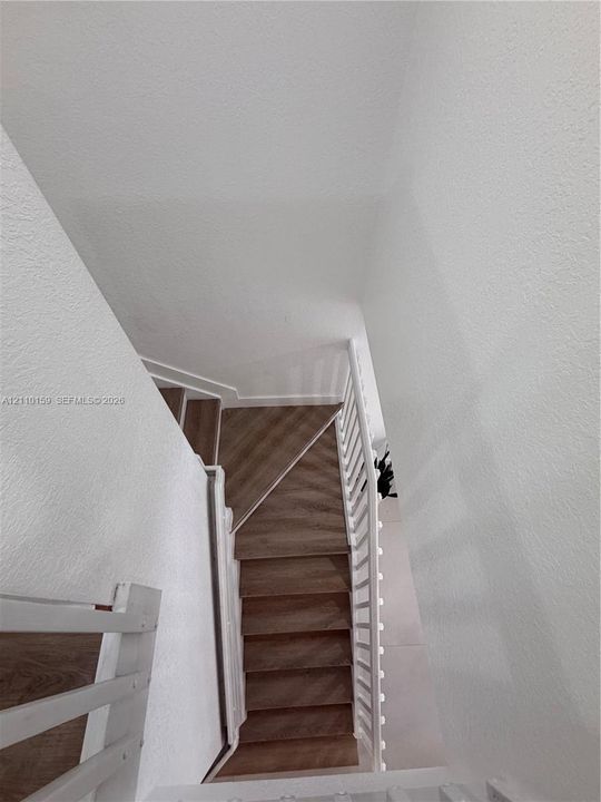 Staircase featuring wood-finish treads and a white painted balustrade