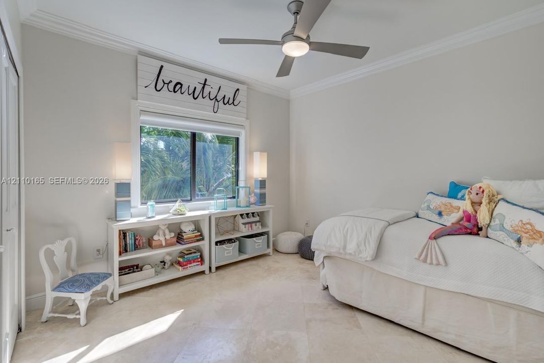 Neutral-toned room featuring large-format tile flooring, crown molding, and a modern ceiling fan with integrated lighting