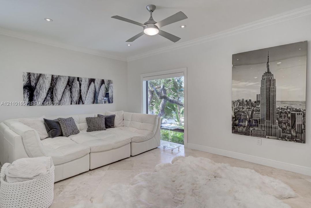 Neutral-toned stone tile flooring, crown molding, recessed lighting, and a center ceiling fan with an integrated light fixture