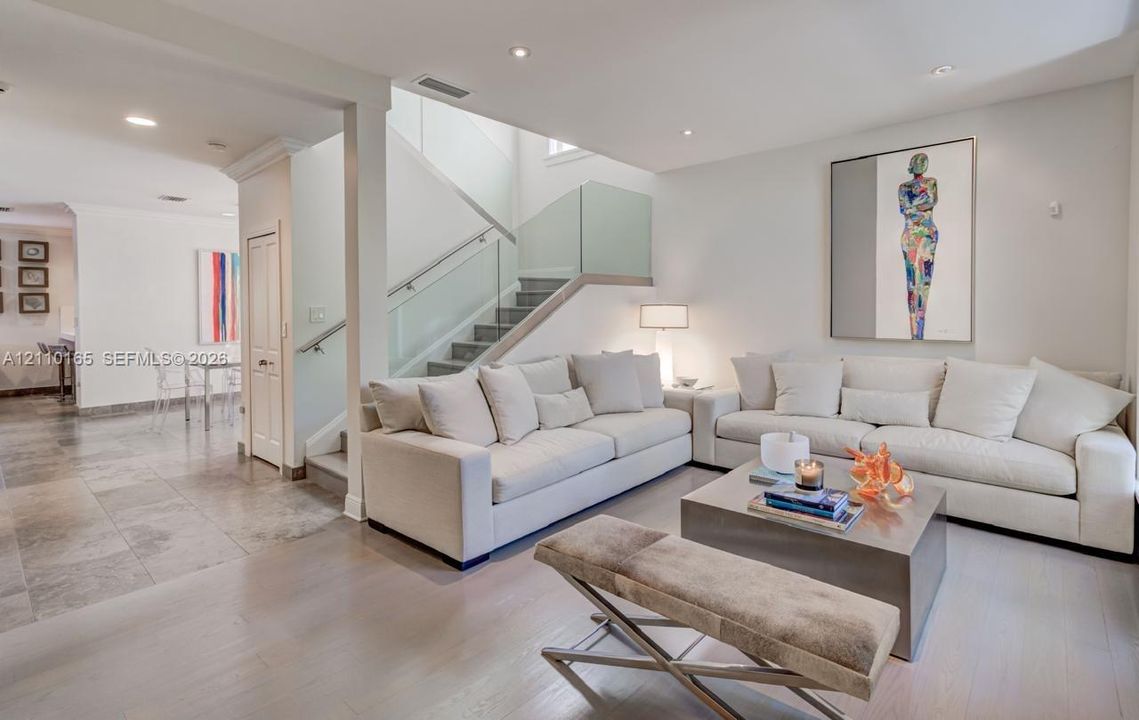 Open-concept interior featuring wood-finish flooring, stone-tile flooring, recessed lighting, and a staircase with glass panel railing