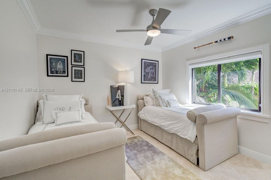 Neutral-toned room featuring crown molding, neutral tile flooring, a multi-blade ceiling fan with an integrated light fixture, and a large window