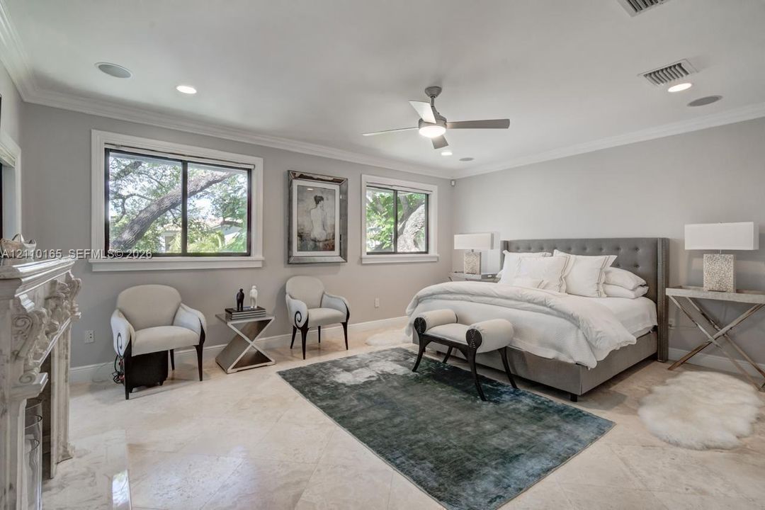 Neutral-toned interior featuring stone flooring, a decorative carved mantel fireplace, recessed lighting, and a ceiling fan with integrated lighting