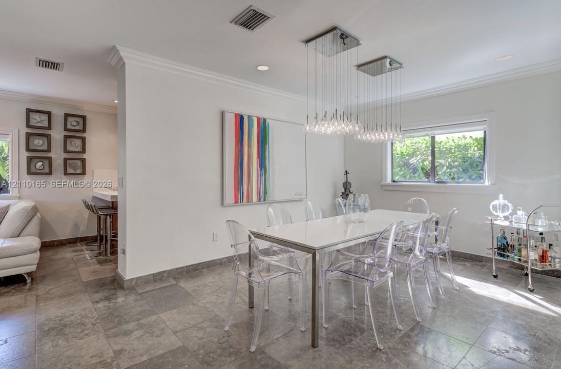 Neutral-toned stone flooring, dual tiered glass pendant light fixtures, and crown molding