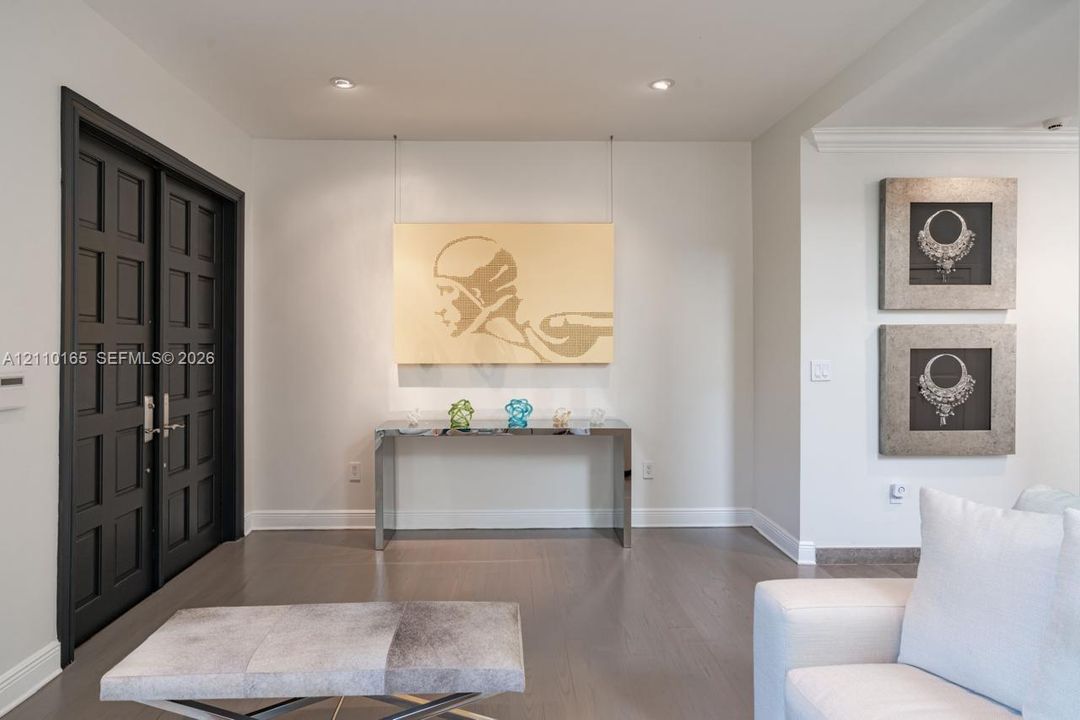 Double entry doors with paneled detailing, wood-finish flooring, and recessed ceiling lighting
