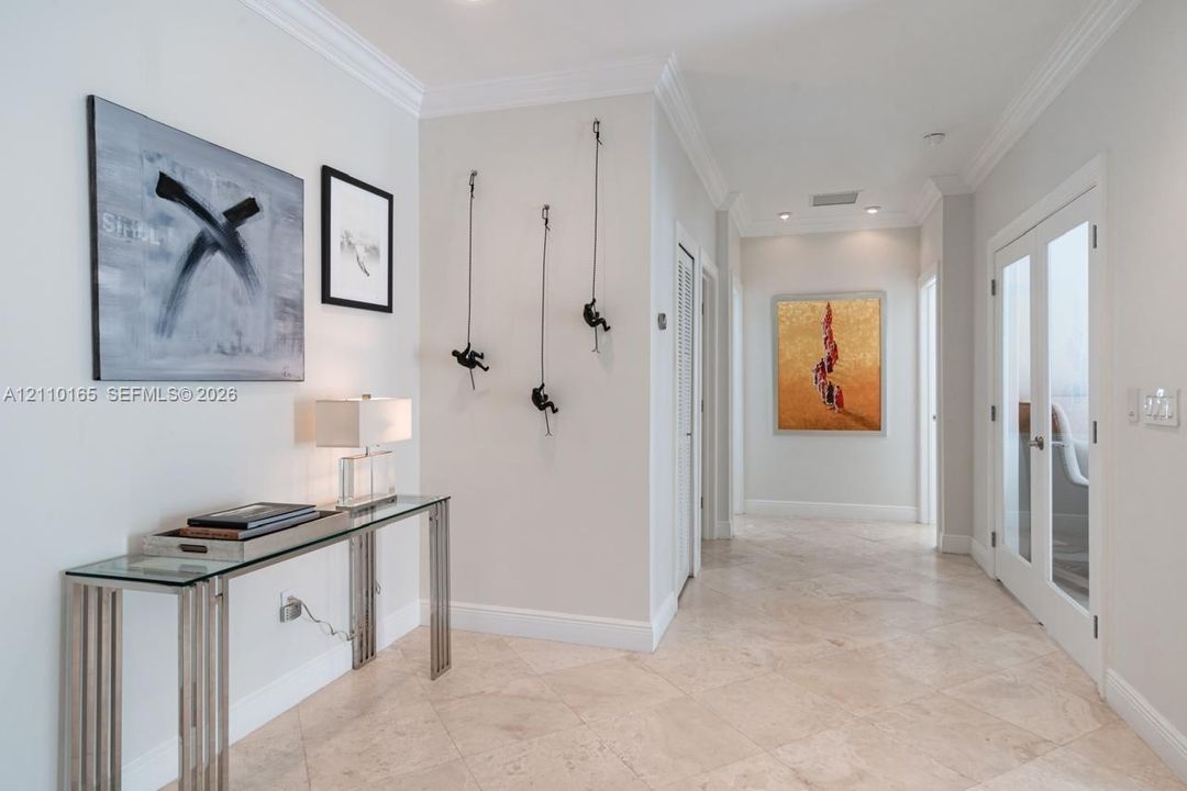 Entryway hall featuring stone flooring, crown molding, and recessed lighting, with double glass-paneled interior doors