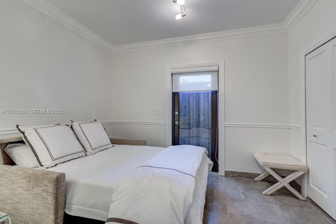 Interior space featuring neutral wall paint, chair rail molding, stone-finish flooring, ceiling-mounted track lighting, and a glass-paneled exterior door