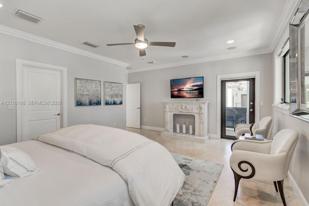 Spacious interior featuring a decorative stone fireplace, neutral stone-finish flooring, crown molding, and a central ceiling fan