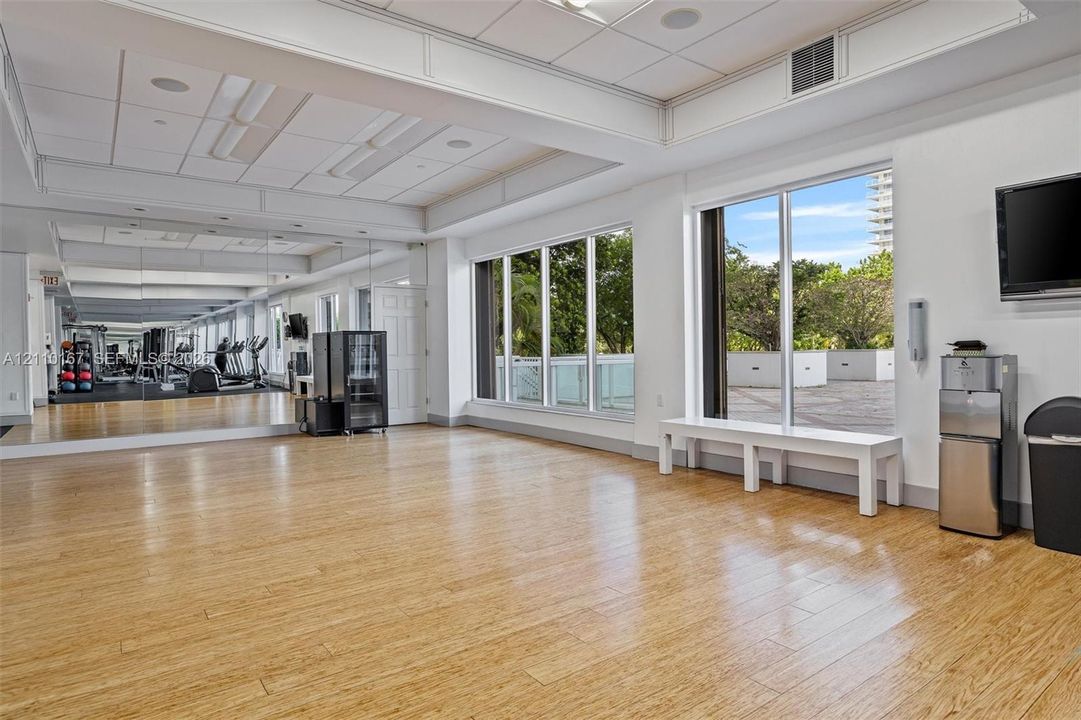 Fitness center featuring wood-finish flooring, floor-to-ceiling mirrored walls, recessed lighting, and expansive windows with natural light