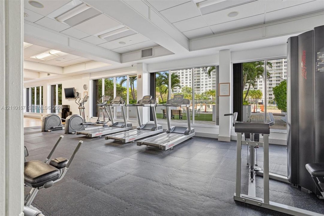 Fitness facility featuring rubberized flooring, high-contrast recessed ceiling lighting, and expansive floor-to-ceiling glass windows