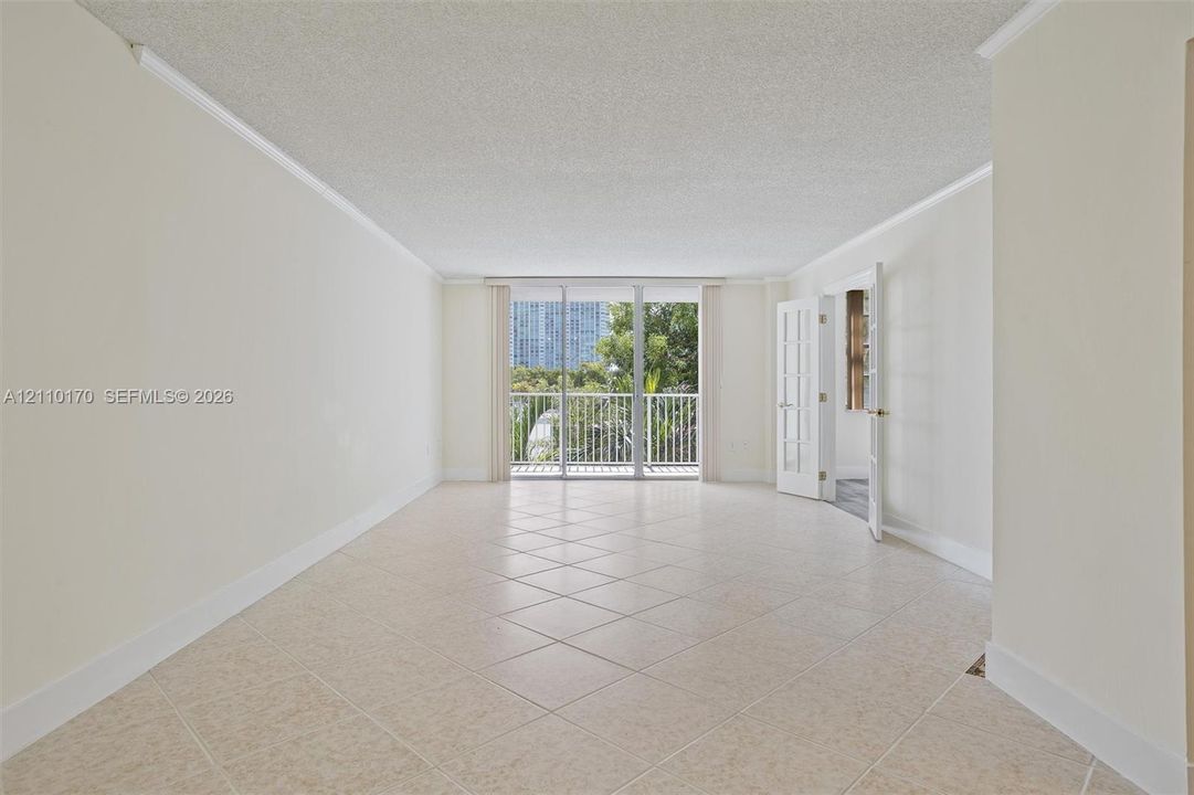 Neutral-toned ceramic tile flooring, crown molding, sliding glass doors, and French-style doors