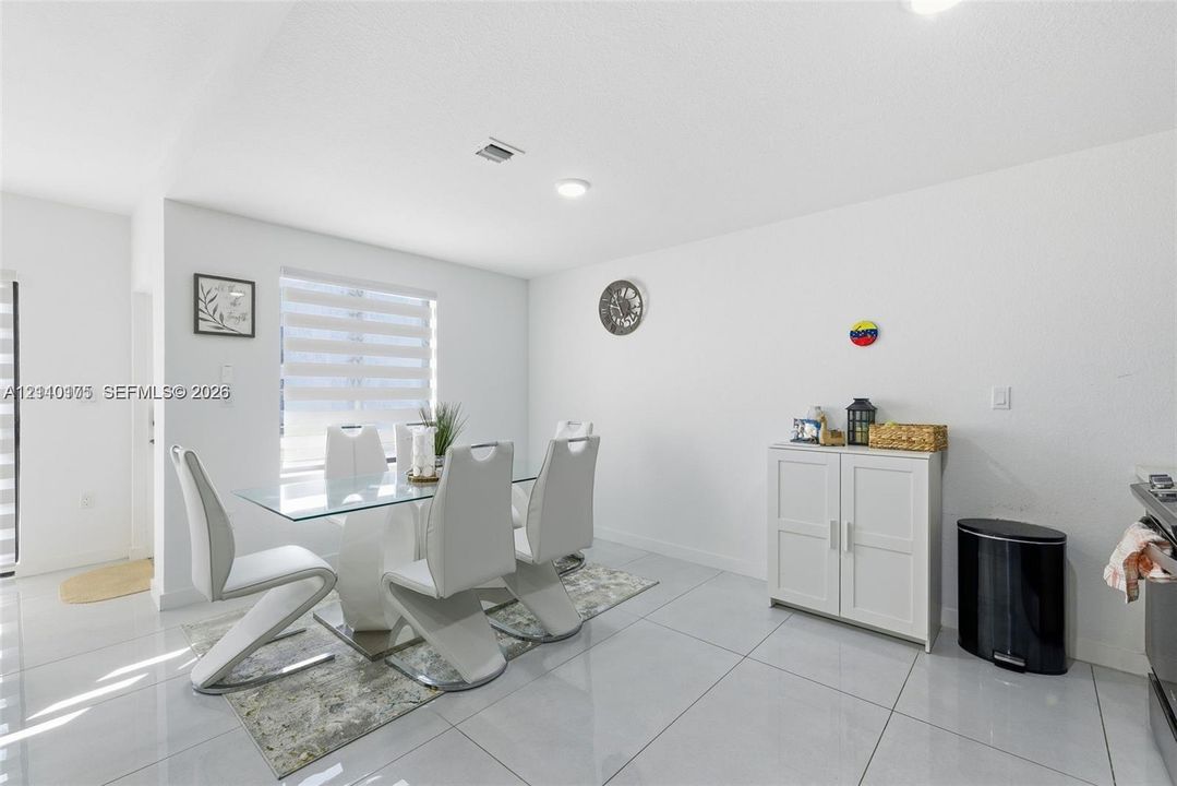 Open-concept dining area featuring large-format tile flooring, recessed lighting, and dual-layered window shades
