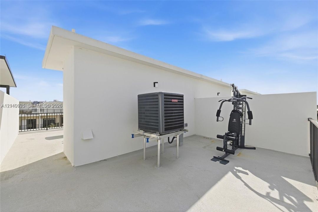 Rooftop terrace featuring smooth concrete flooring, solid perimeter walls, and metal railings