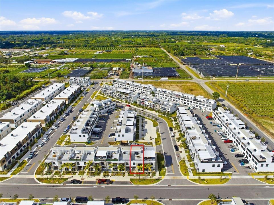 Aerial view featuring multi-level townhome architecture with flat rooflines, private rooftop terraces, and dedicated on-site parking within a residential community