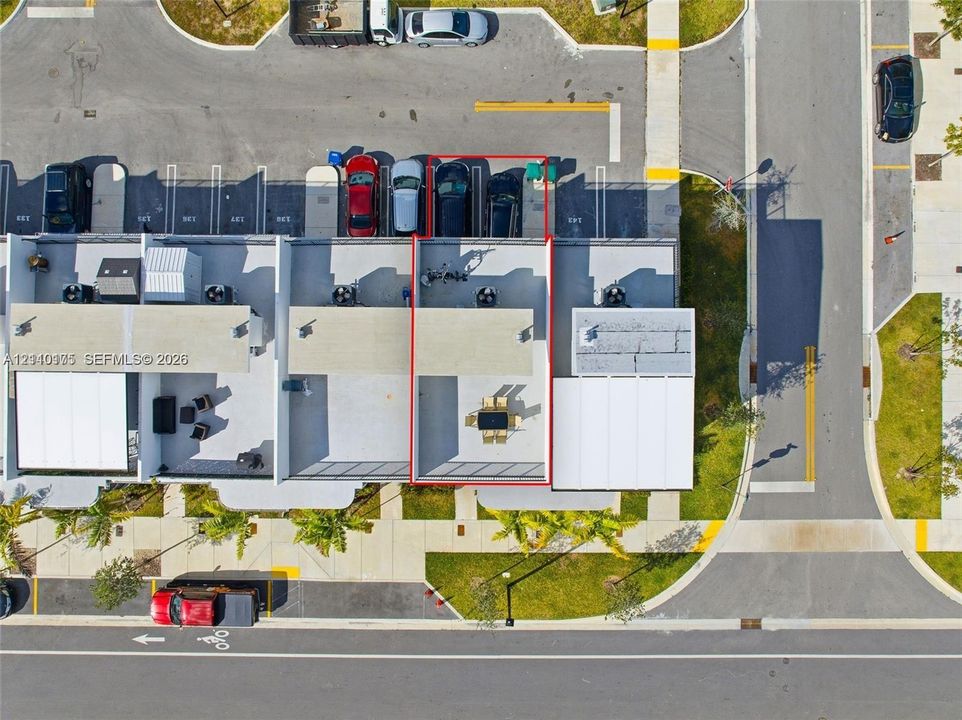 Aerial perspective of a multi-level property featuring a rooftop terrace, designated surface parking, and exterior lighting fixtures