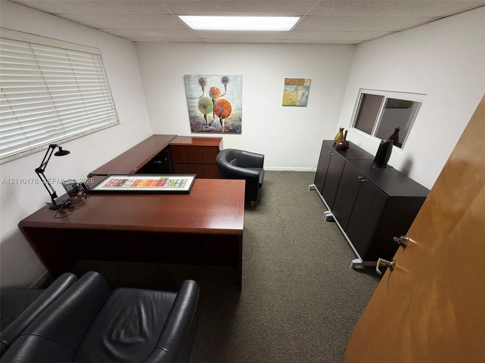 Room featuring neutral wall-to-wall carpeting, dual windows with horizontal blinds, and a suspended drop ceiling