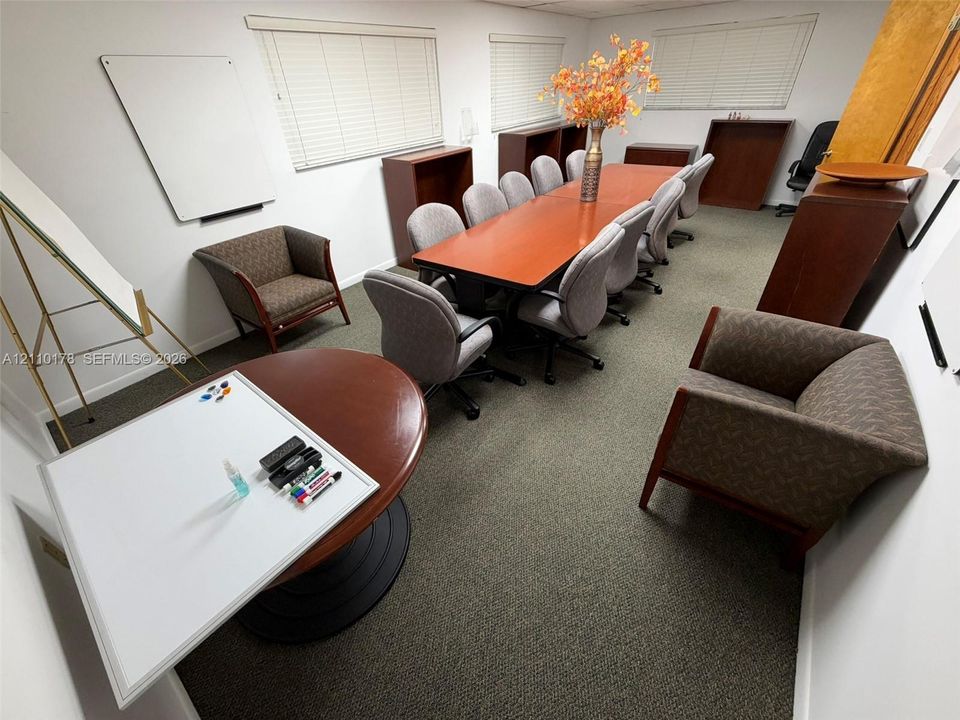 Meeting room featuring wall-to-wall carpeting, wood-finish built-in cabinetry, and horizontal window blinds
