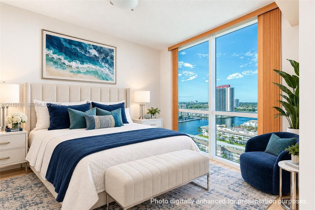 Floor-to-ceiling windows featuring expansive exterior water and urban scenery, accompanied by a neutral-toned upholstered wall-mounted headboard