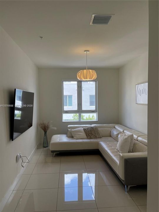Interior space featuring large-format tile flooring, neutral wall tones, a modern drum pendant light fixture, and a window with a multi-pane configuration