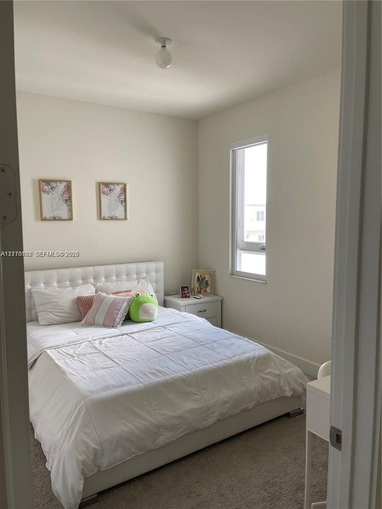 Neutral-toned room featuring wall-to-wall carpeting and a tall, vertical window