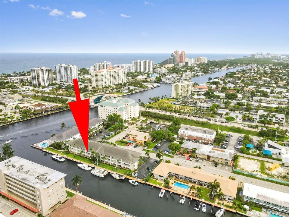 Aerial perspective of a multi-story waterfront condominium featuring canal frontage and boat dockage