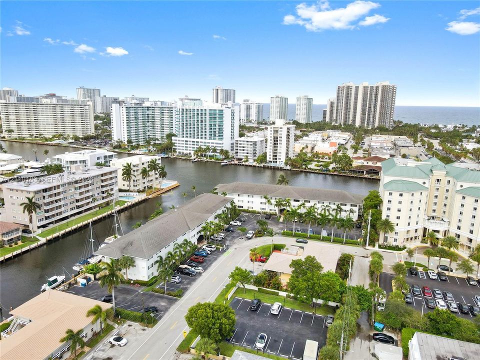 Aerial perspective featuring waterfront canal access, proximity to coastal skyline, mature palm landscaping, and dedicated surface parking