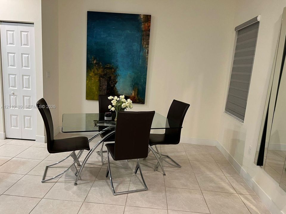 Light-colored tile flooring, neutral wall tones, six-panel interior door, and adjustable roller shade