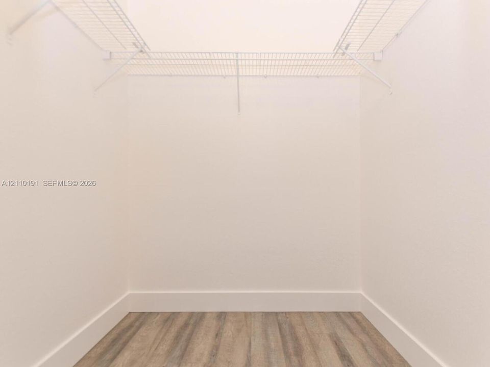 Walk-in closet featuring white wire shelving and wood-finish flooring