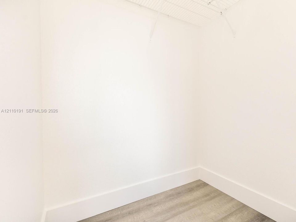 Walk-in closet featuring neutral walls, wood-finish flooring, and white wire shelving