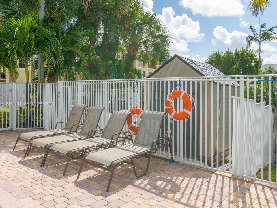 Paver patio with a white metal perimeter fence and an onsite storage shed